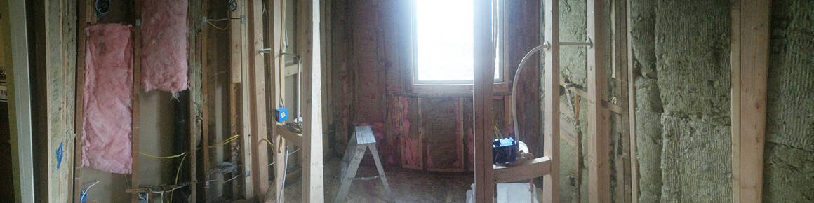 View from doorway with walls for shower framed in with electrical and plumbing installed.