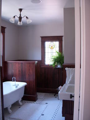 New bathroom with many historical features including: a claw foot tub, penny tile, wainscoting, stained glass & antique lighting. 